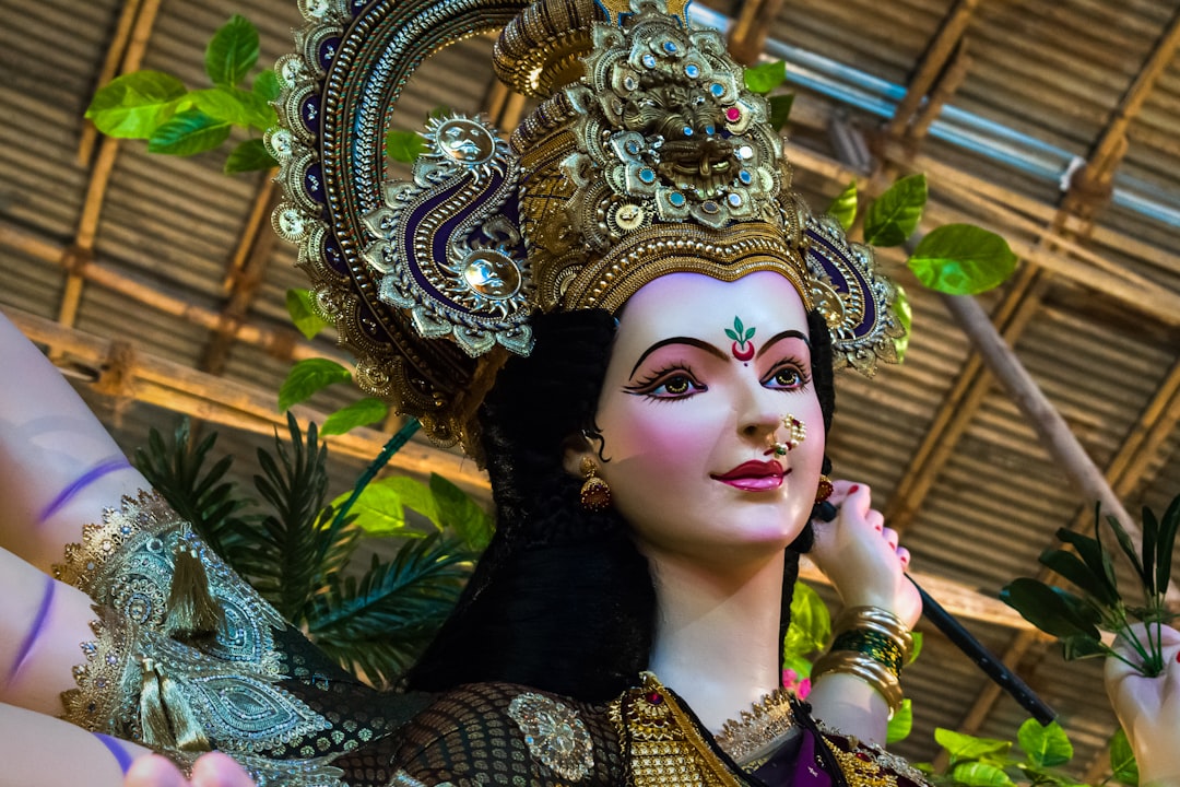 woman in gold and green floral dress wearing gold crown, A beautiful idol of Maa Durga at a workshop in Mumbai during Na