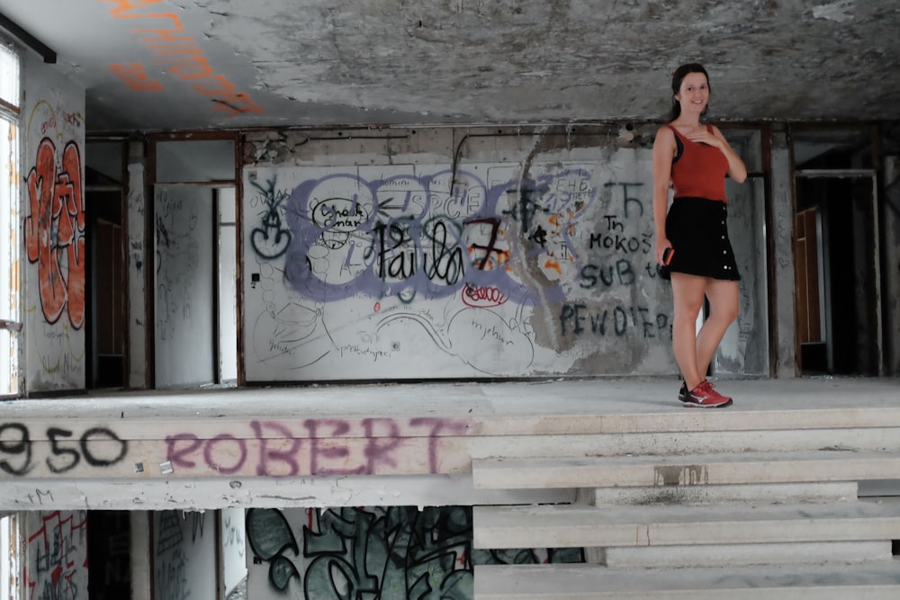 Femme en jupe noire debout à côté d’un mur de graffiti