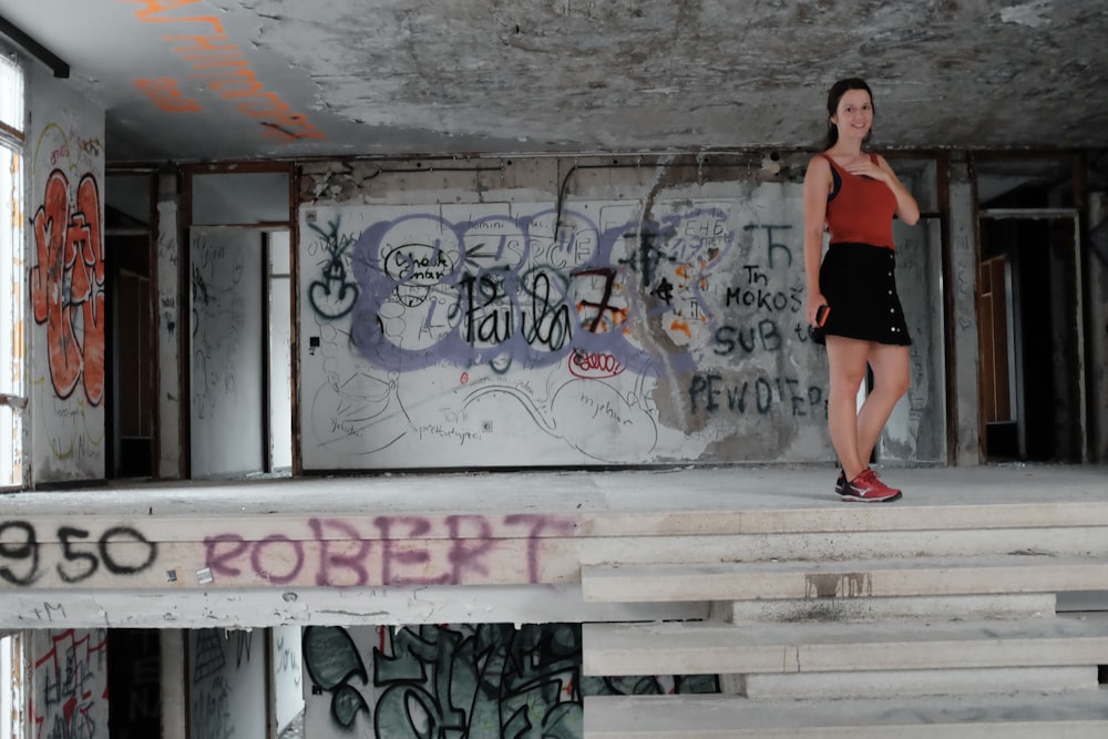 Mujer en falda negra de pie junto a la pared de graffiti