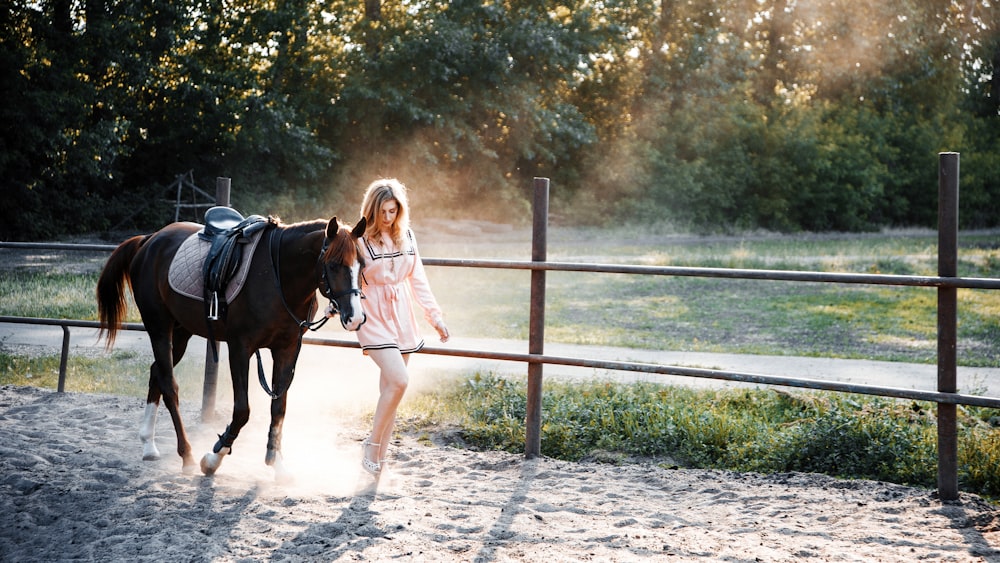 girl in pink jacket riding on black horse during daytime