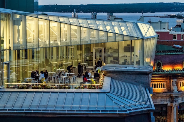 people sitting on bench near glass building during daytime