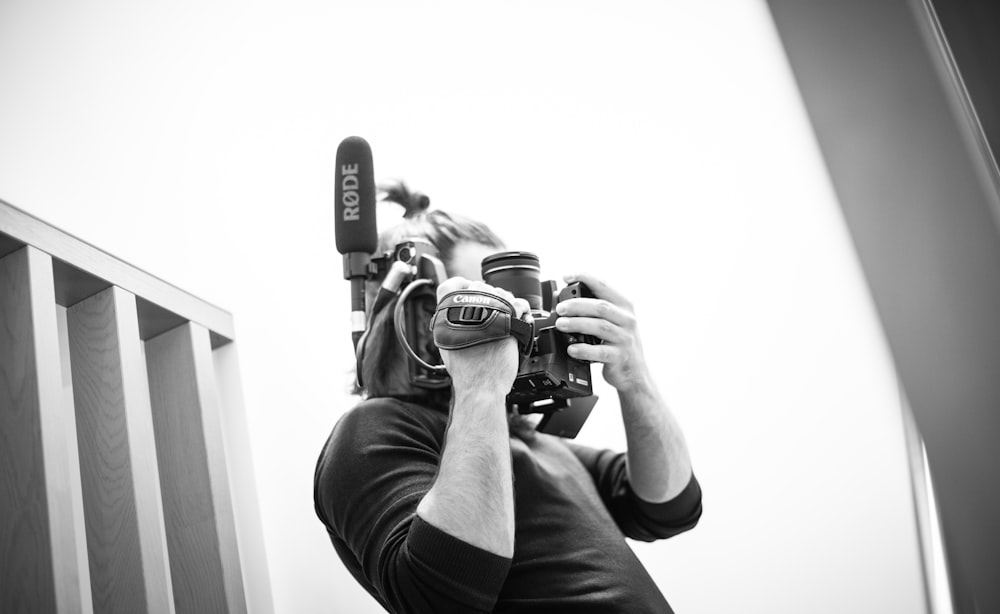 man in black t-shirt holding black dslr camera