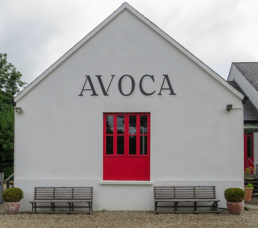 a white building with a red door and two benches in front of it