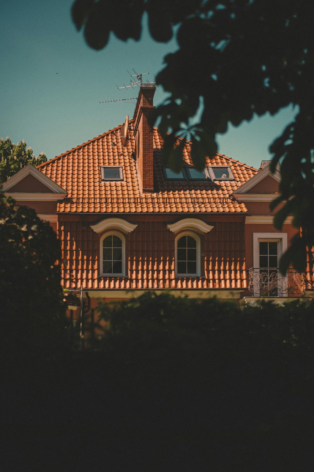 Braunes und weißes Betonhaus, tagsüber von grünen Bäumen umgeben