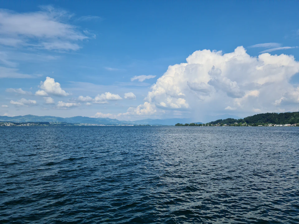 Serene lake surrounded by mountains with calm water reflecting blue sky's hue