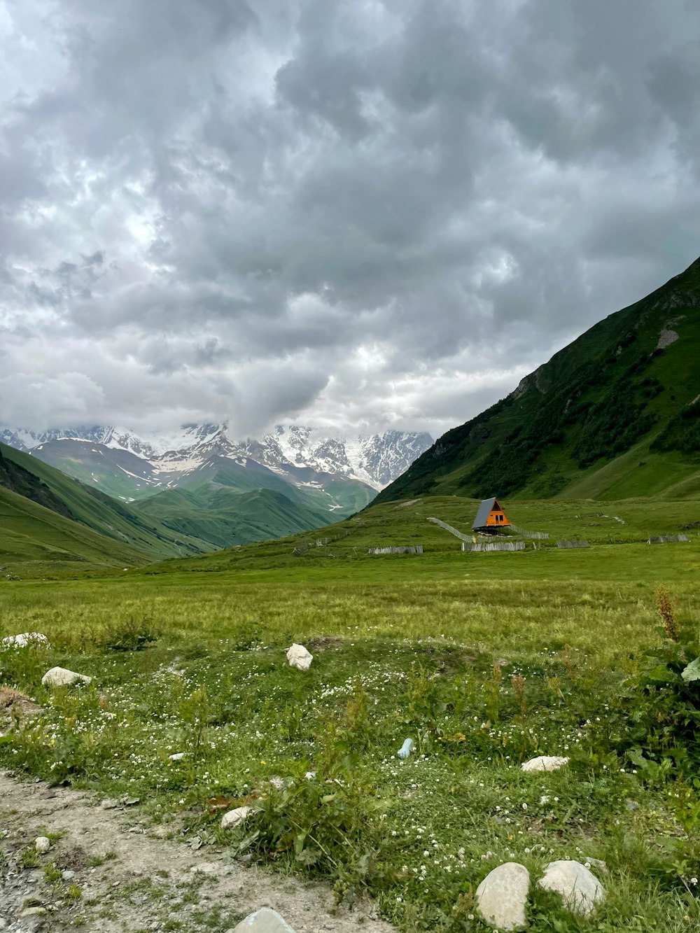 green grass field near mountains under cloudy sky during daytime