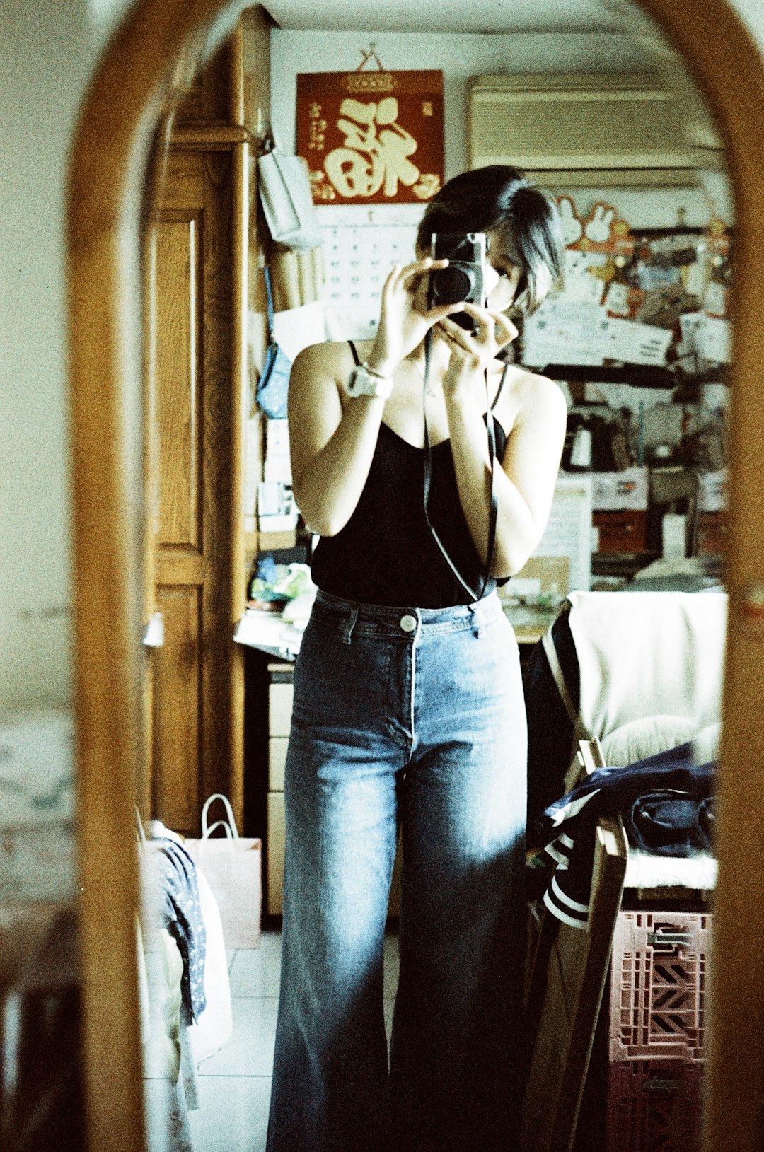 woman in black tank top and blue denim jeans taking selfie