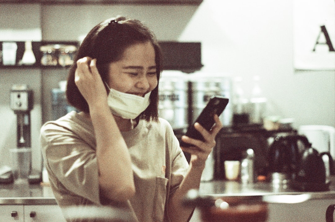 woman in white dress shirt holding smartphone