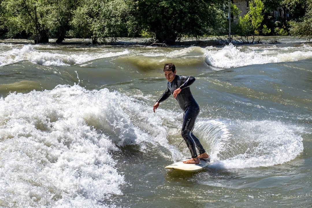 woman in black wetsuit riding yellow surfboard on water during daytime