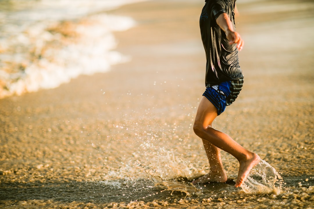 person in black shirt and blue shorts running on water during daytime