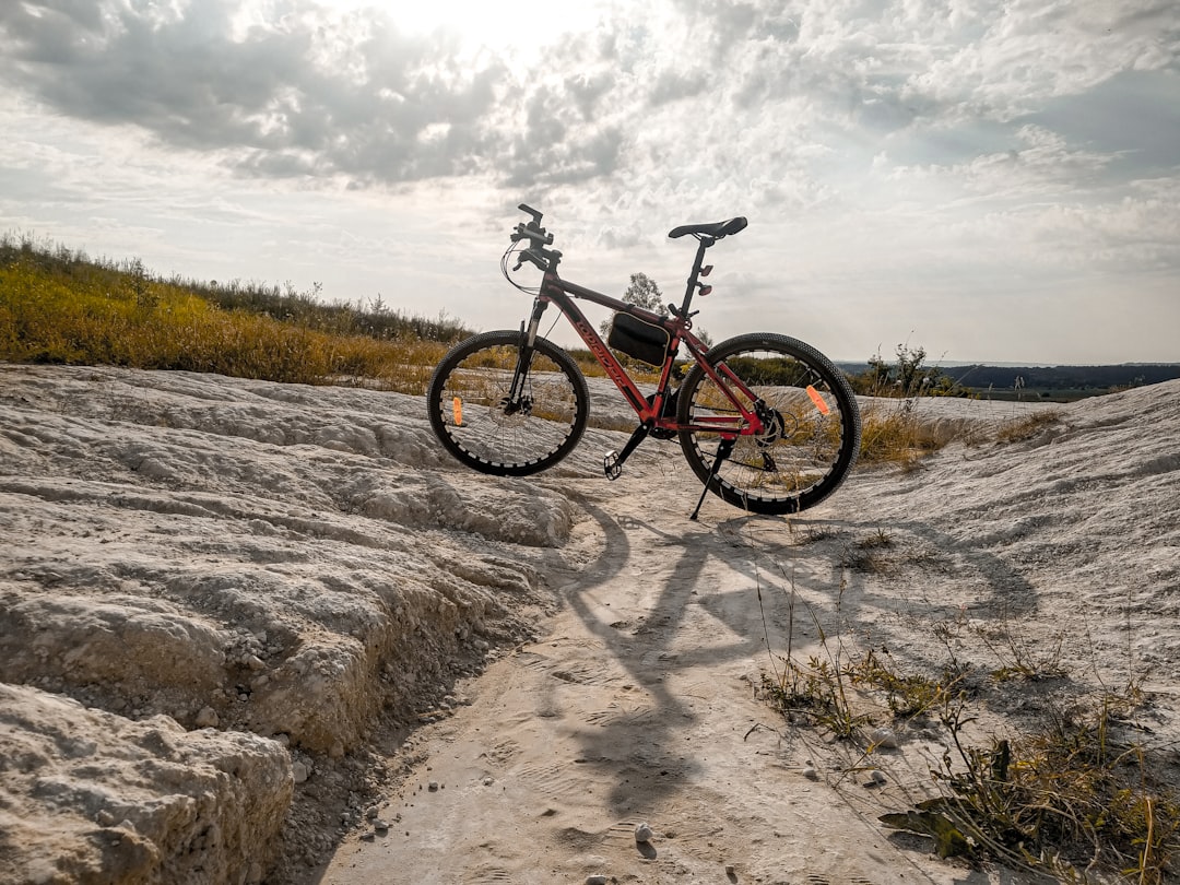 black and red hardtail mountain bike on brown field under white clouds during daytime