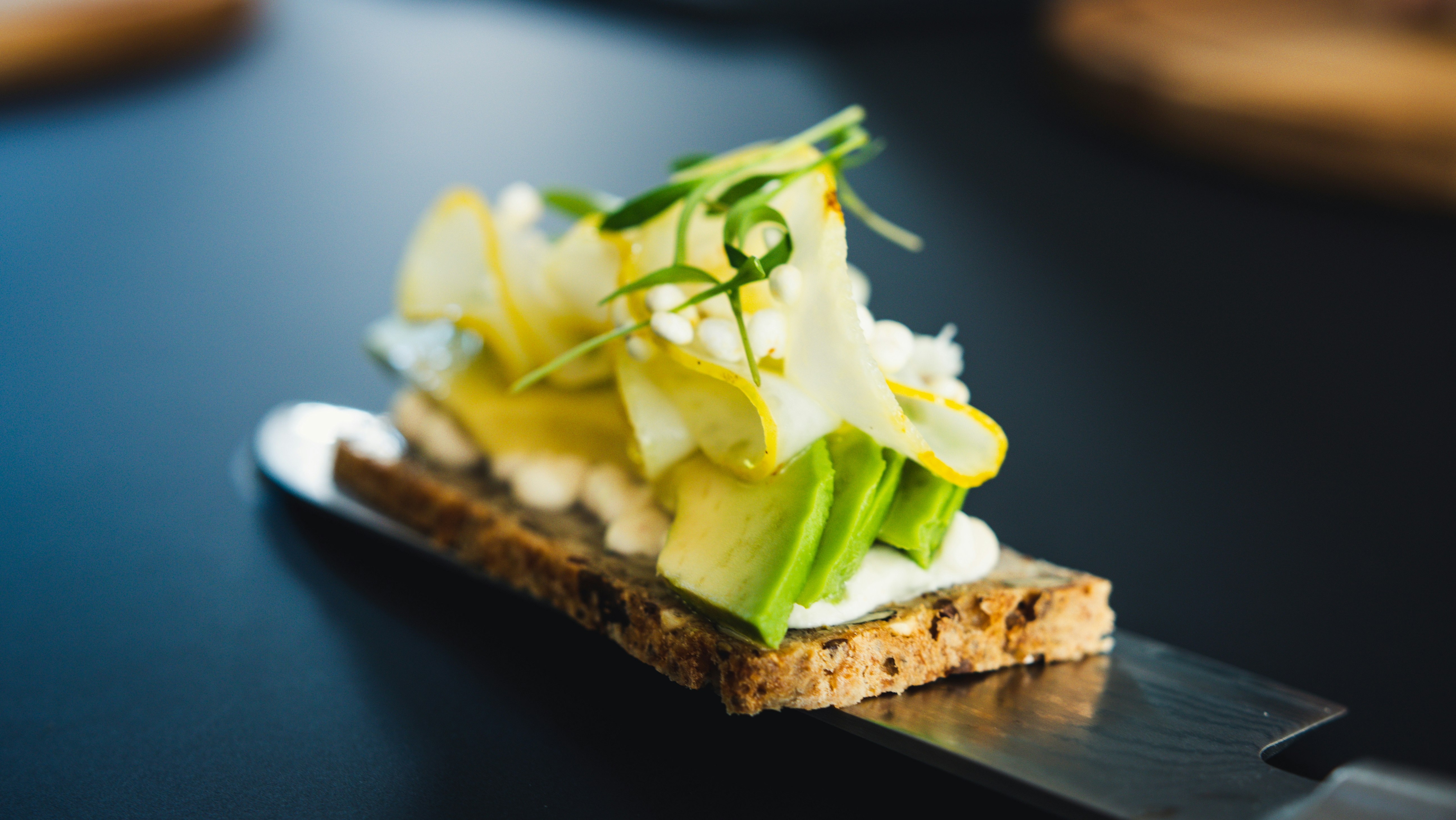 sliced bread with white cream and green vegetable on white ceramic plate