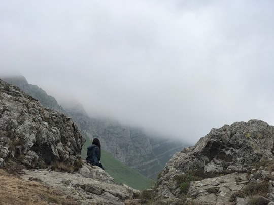 man in blue jacket sitting on rock mountain during daytime in Mount Khustup Armenia