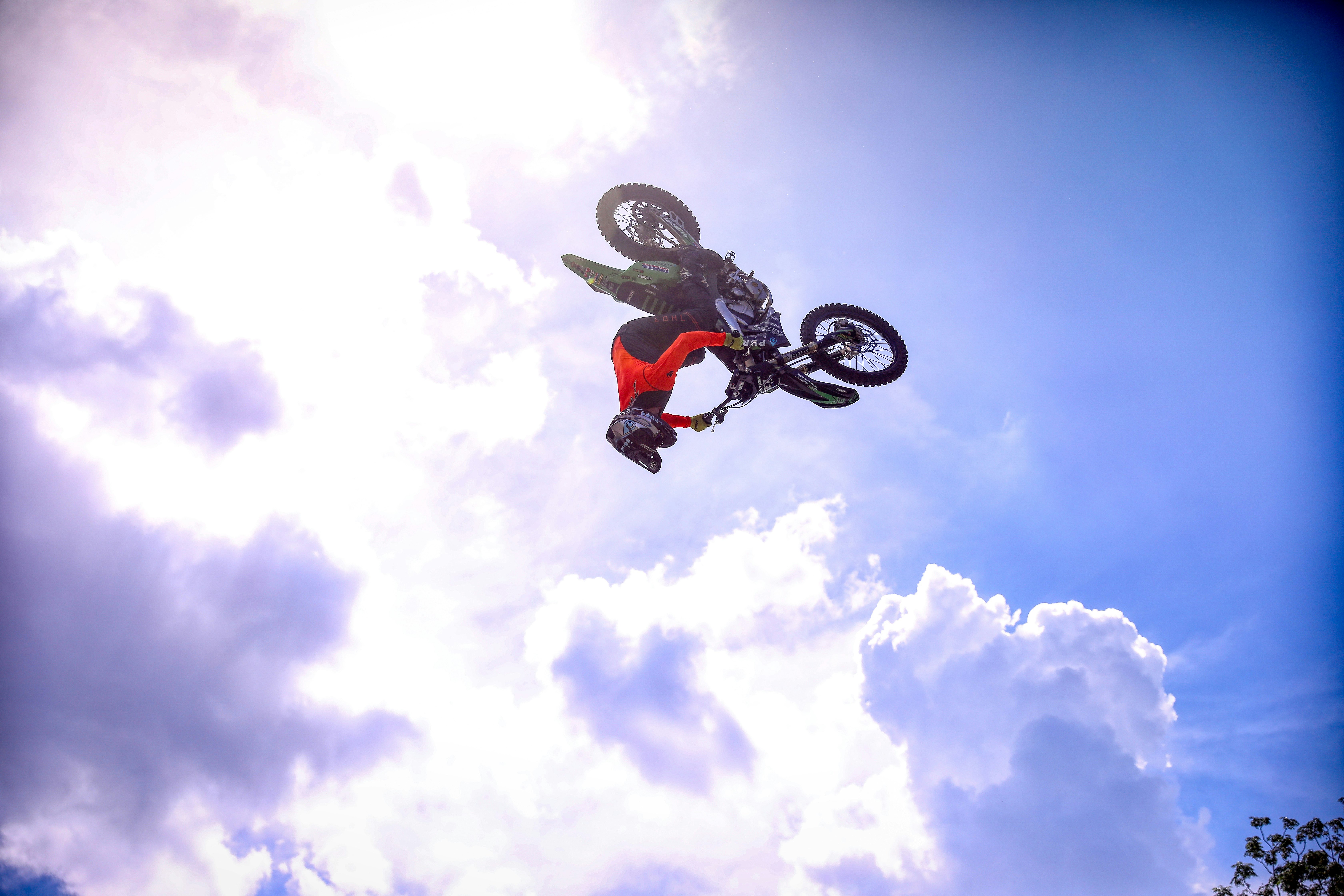 man riding on black bmx bike doing stunts under blue and white sunny cloudy sky during