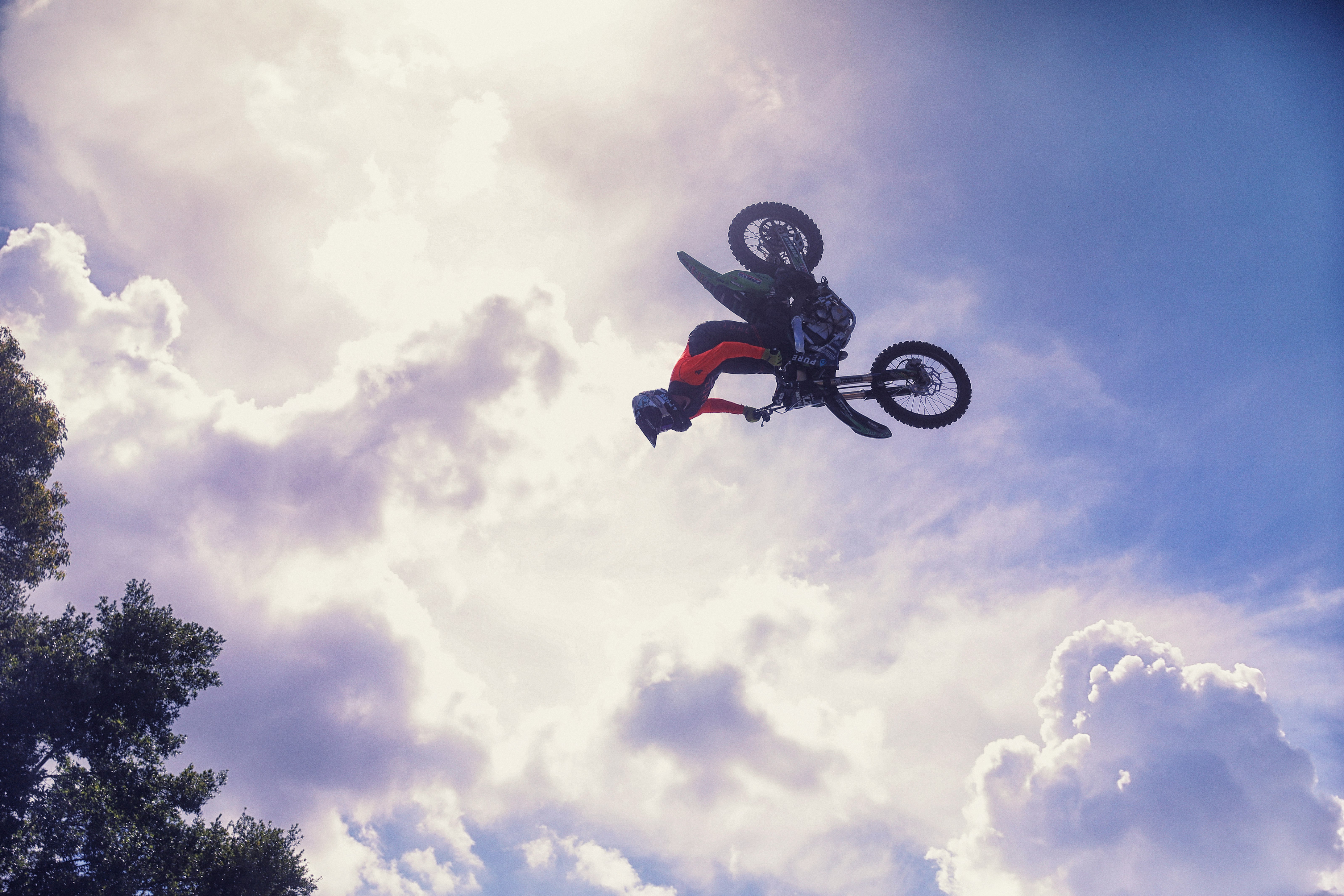 man riding on motocross dirt bike under white clouds and blue sky during daytime