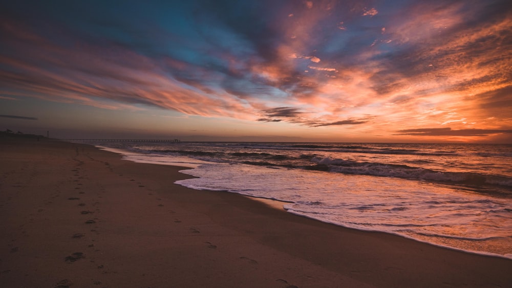 sea waves crashing on shore during sunset