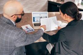 man in black suit jacket holding white printer paper