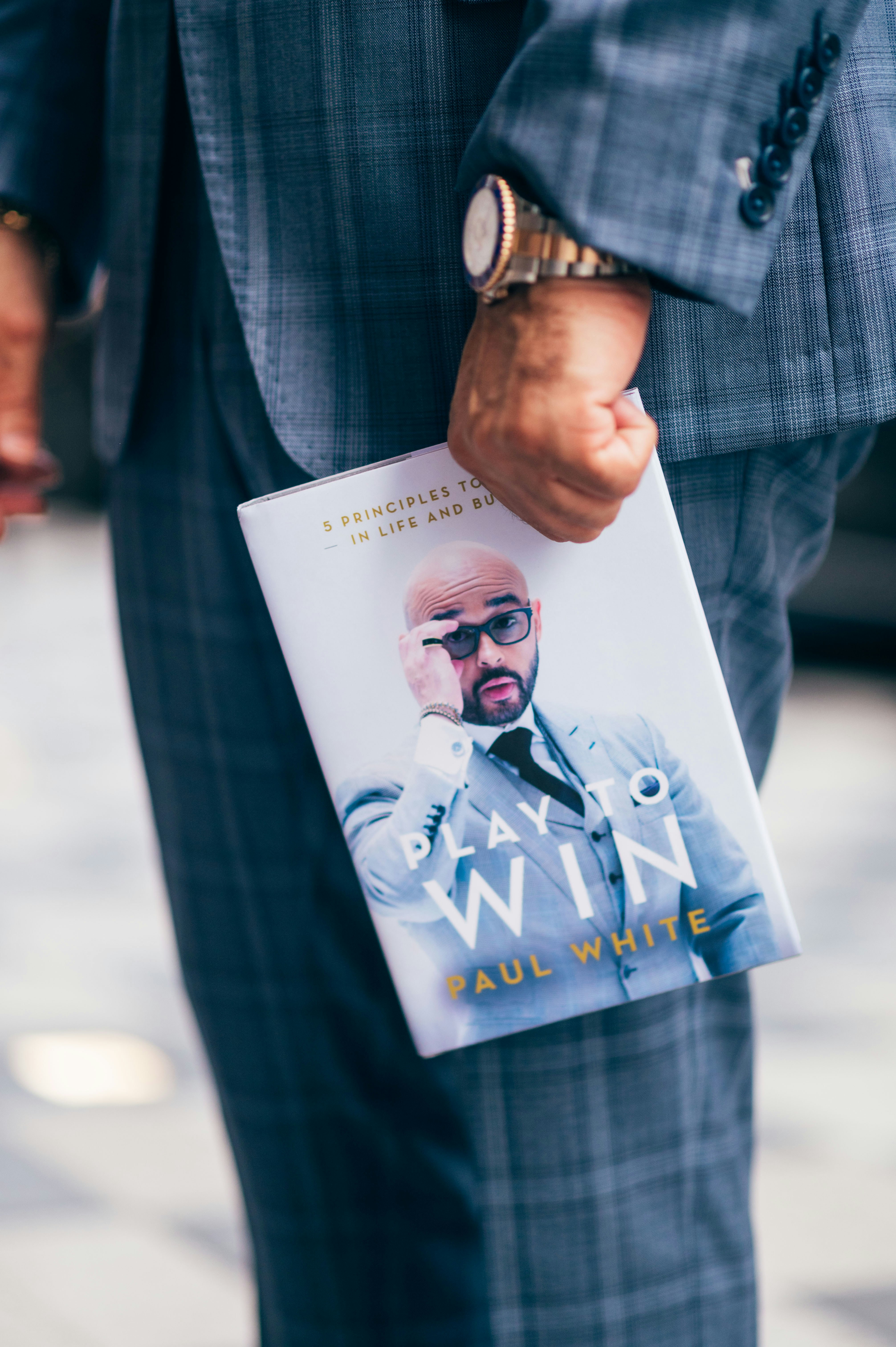 man in black and white plaid blazer holding white printer paper