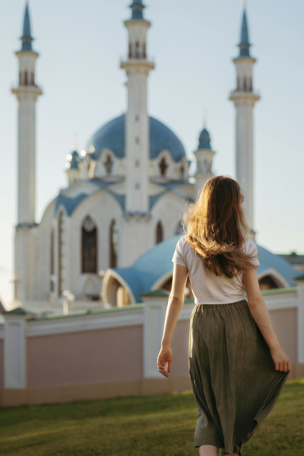 woman in white sleeveless shirt and black skirt standing in front of white concrete building during