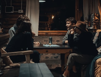 man in black jacket sitting on brown wooden chair
