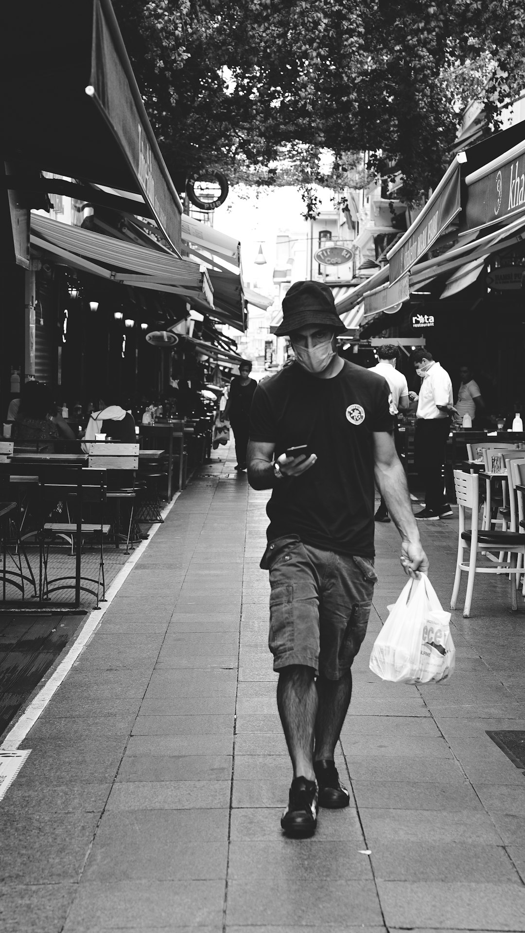 man in black crew neck t-shirt and white cargo shorts walking on sidewalk during daytime