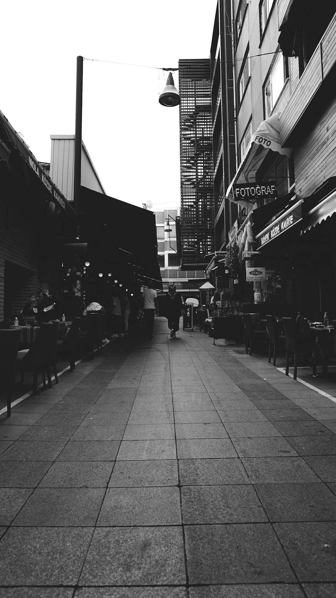 grayscale photo of people walking on sidewalk near buildings