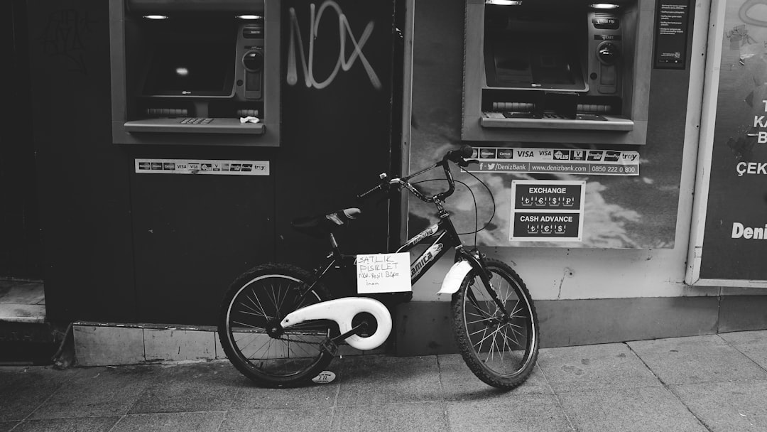 grayscale photo of bicycle parked beside wall