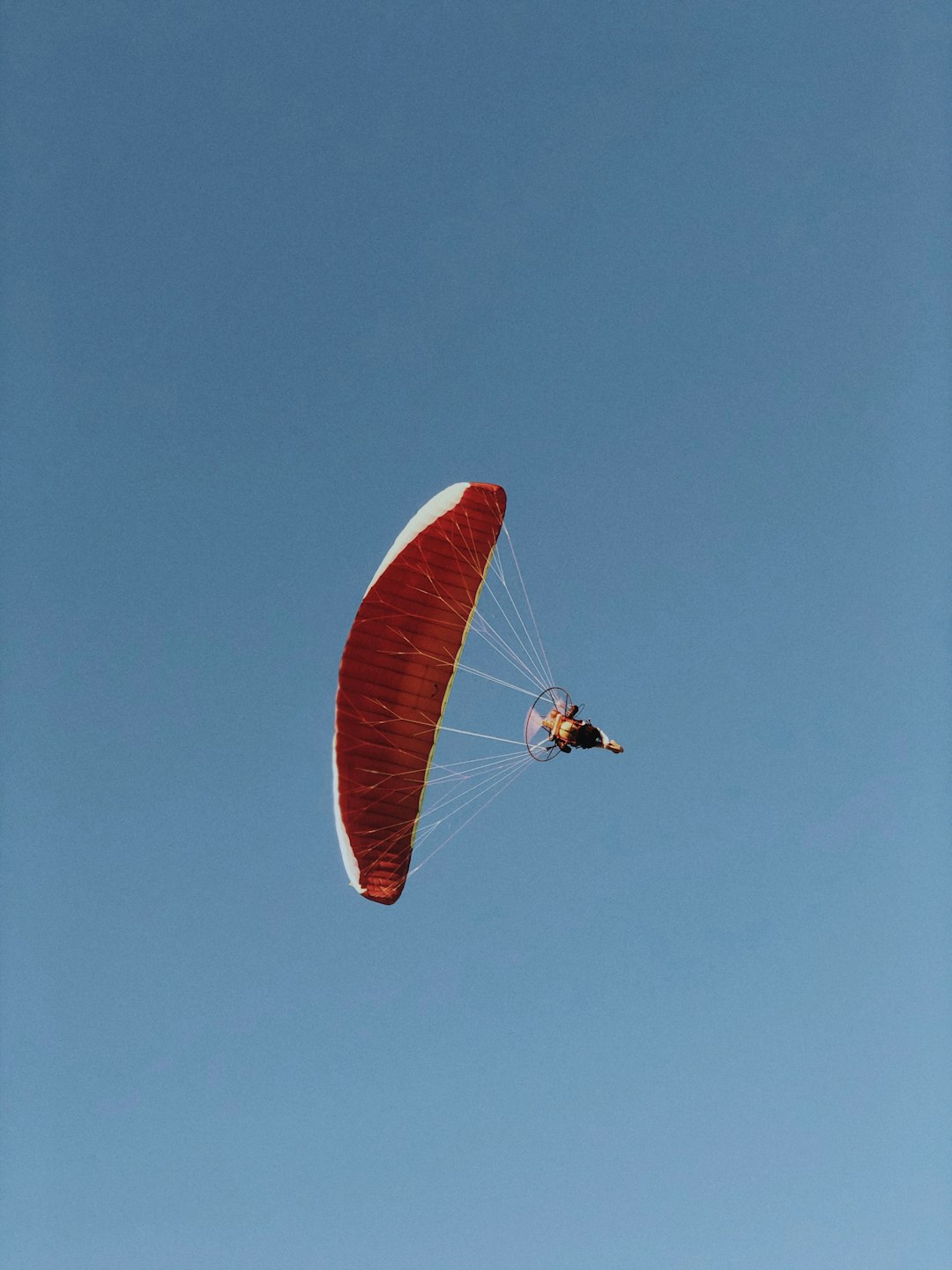 person in red parachute under blue sky during daytime