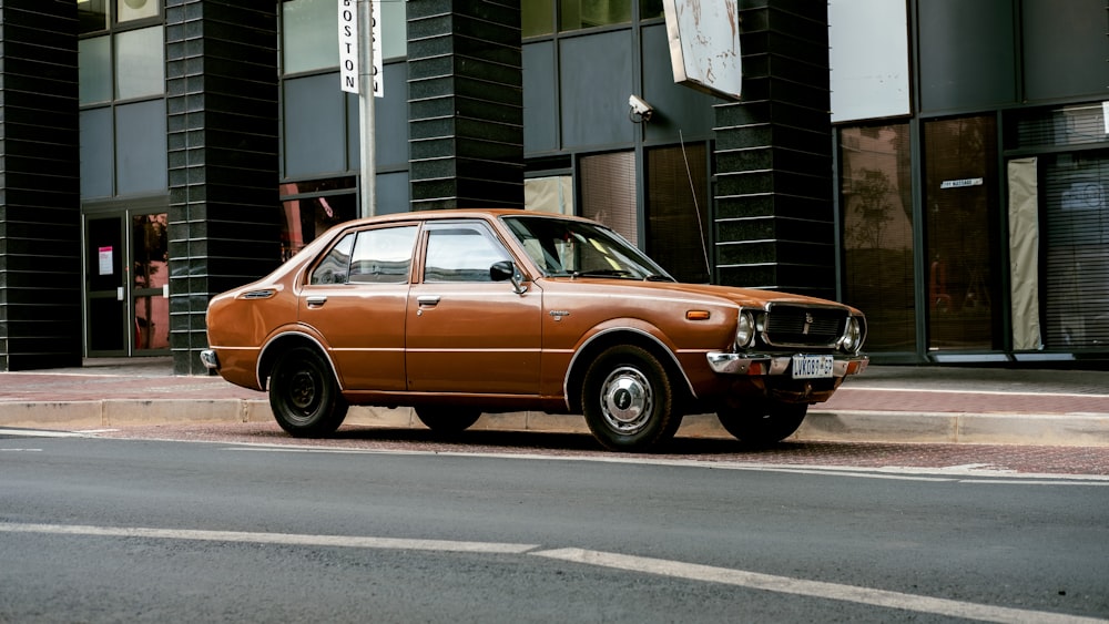 brown sedan parked beside gray concrete building during daytime