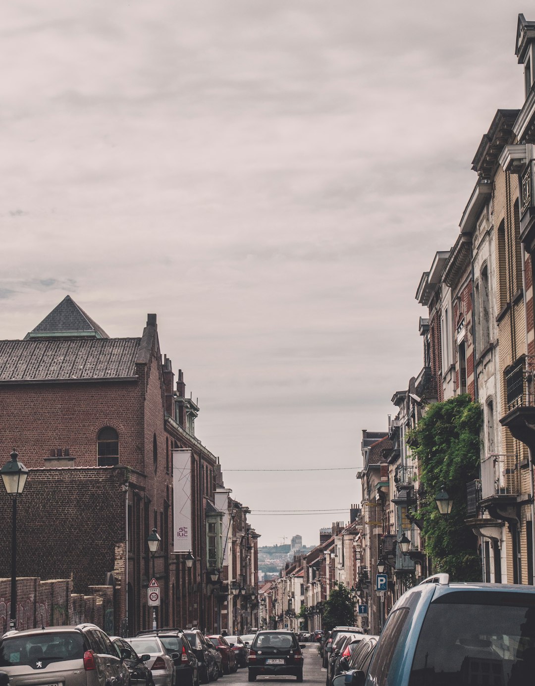 cars parked beside brown concrete building during daytime