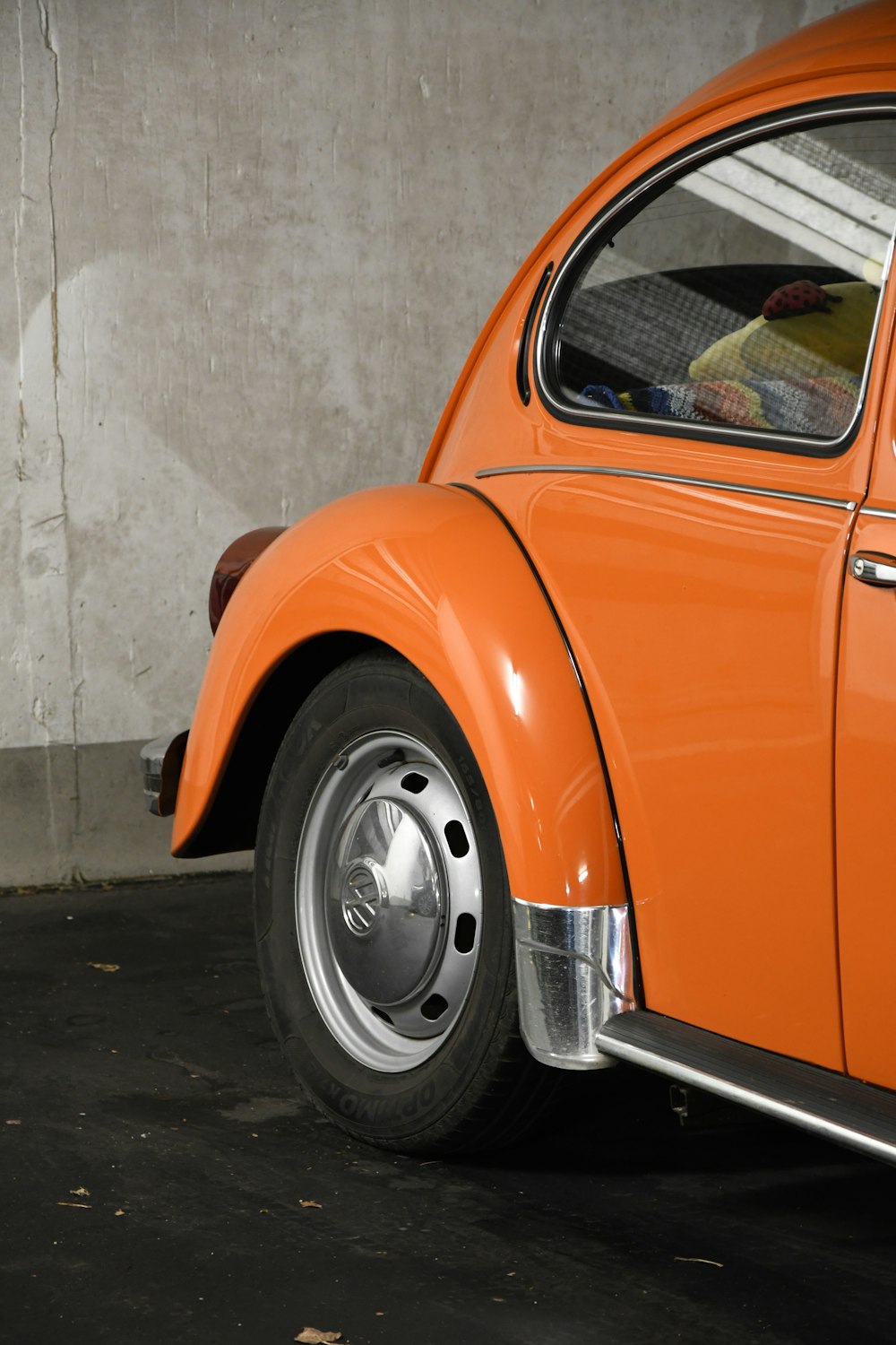 orange car parked beside white wall