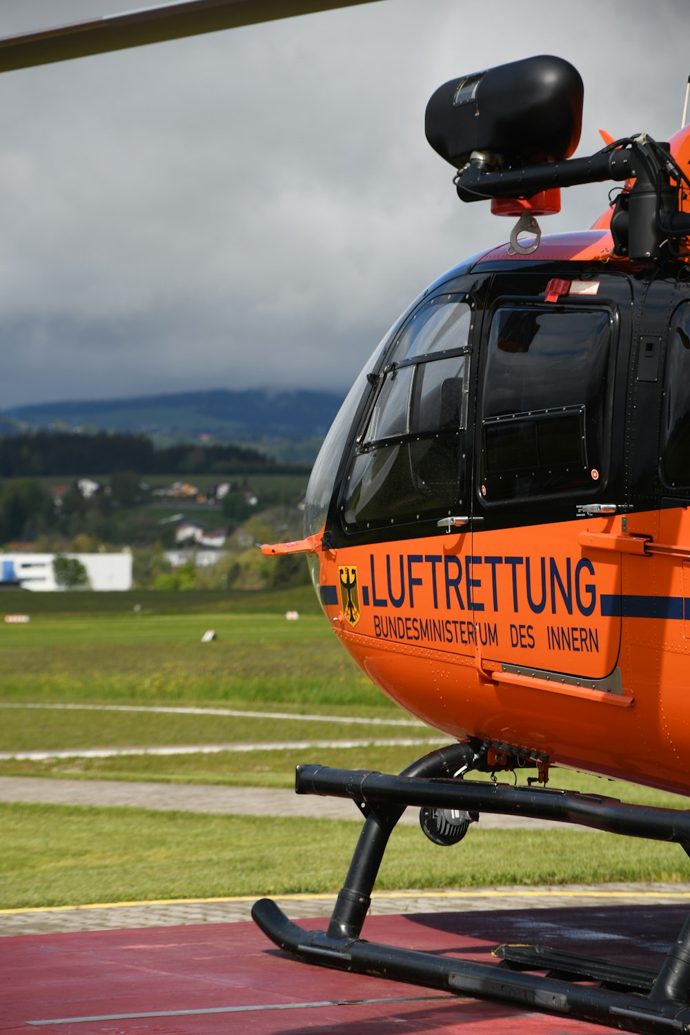 Helicóptero naranja y negro en campo de hierba verde durante el día