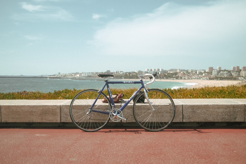 bicicleta azul da cidade estacionada no pavimento de concreto marrom perto do corpo de água durante o dia