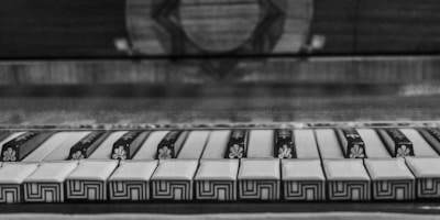 A close-up of a piano keyboard featuring unique, ornate patterns on some keys. The image is in black and white, with detailed decorations on the piano keys that resemble intricate floral and geometric designs.