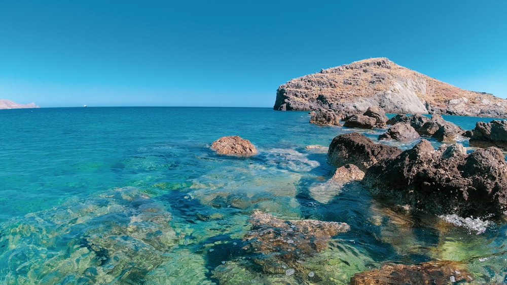 brown rock formation on blue sea under blue sky during daytime