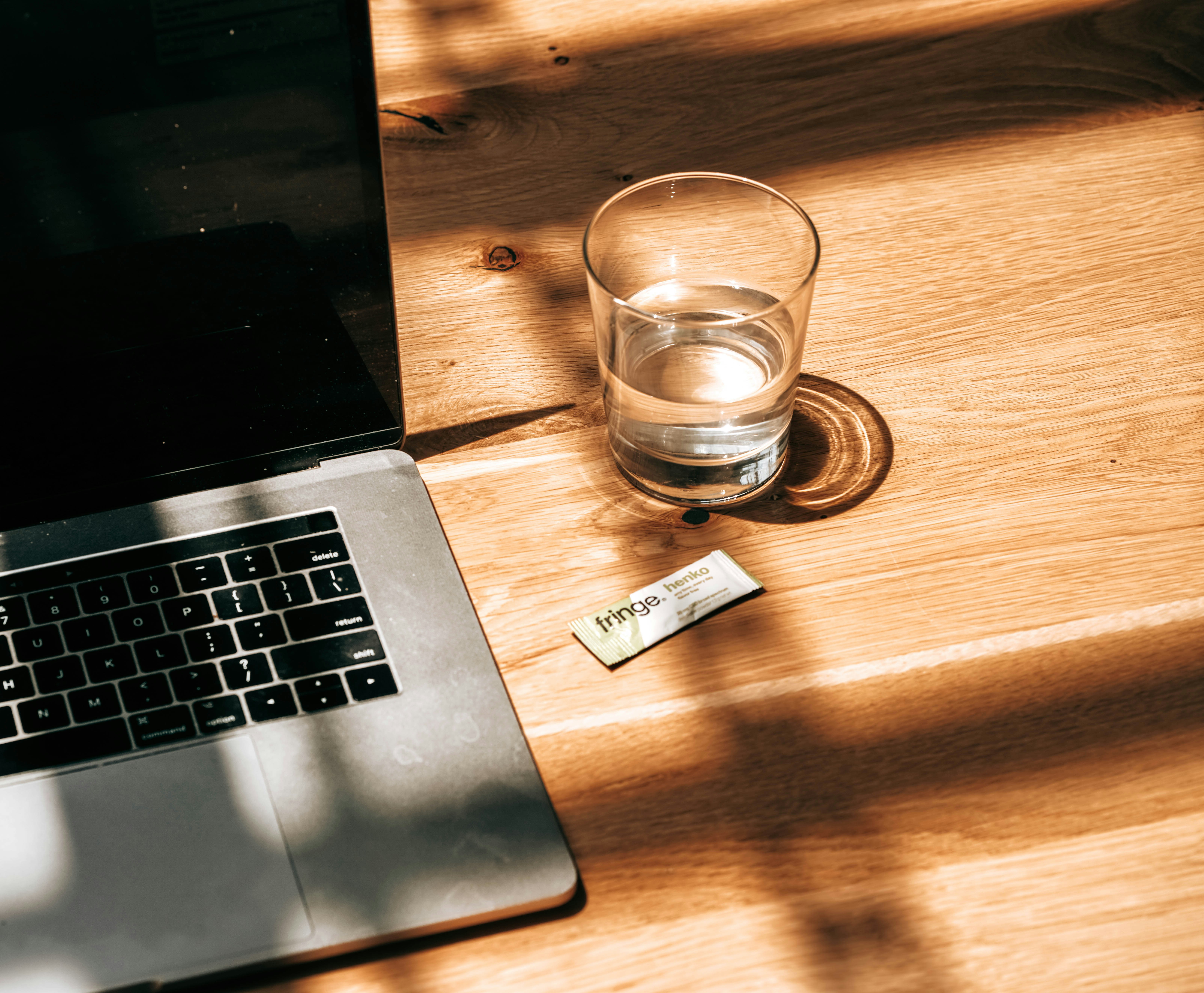 clear drinking glass beside silver macbook