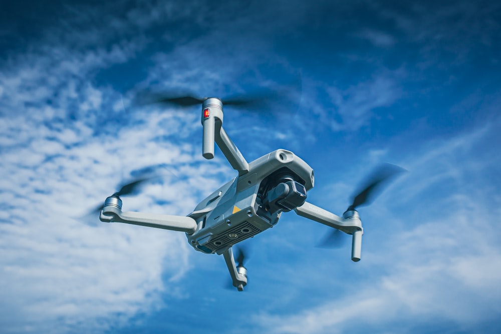 white and black drone flying under blue sky during daytime