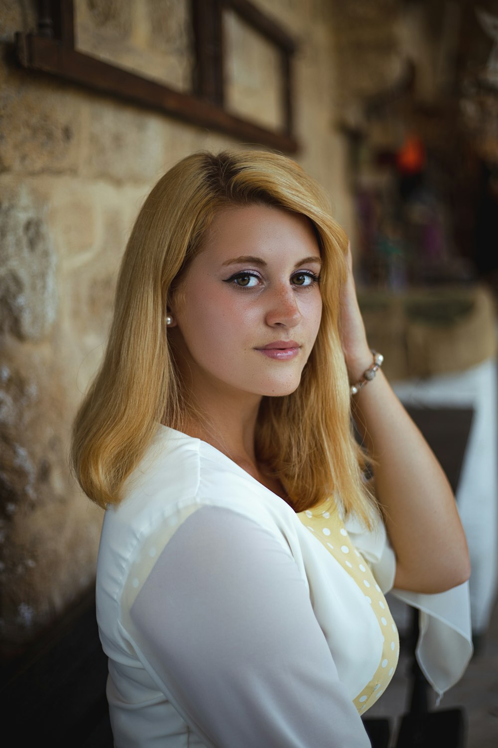 woman in white dress leaning on brown concrete wall