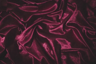 Soft, rich folds of silky red fabric, elegantly draped and creating shadows and highlights that accentuate its luxurious texture.