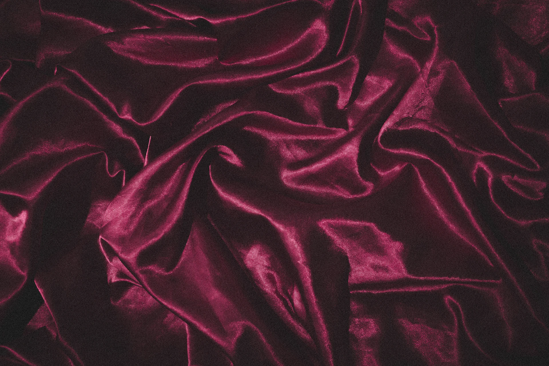A rich burgundy velvet party dress with a classic silhouette and delicate draping, photographed with gentle shadows highlighting the plush texture.
