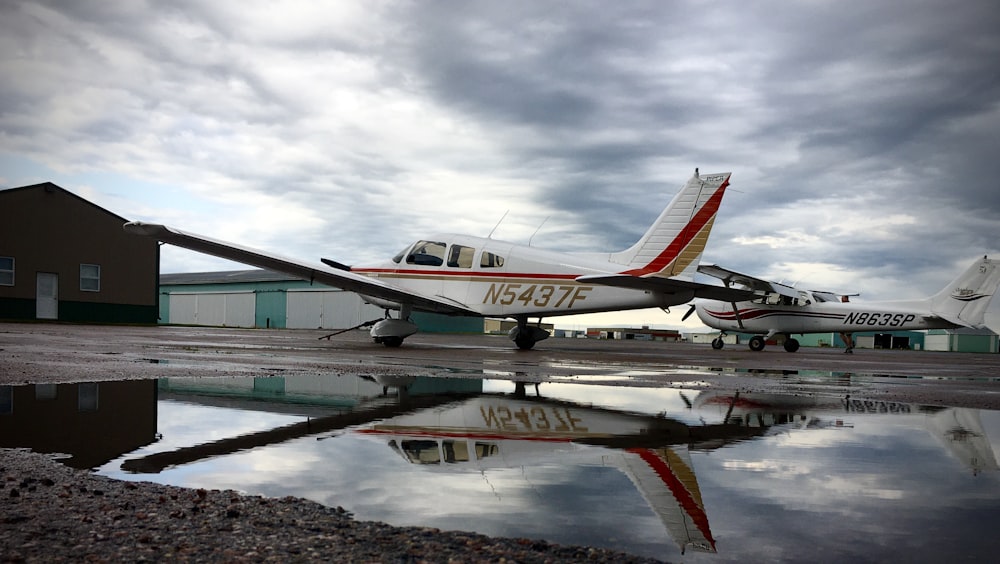 white and red airplane on brown ground under white clouds during daytime