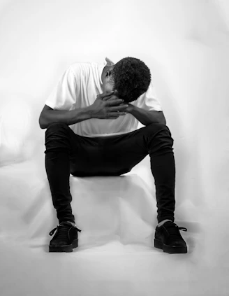 man in white t-shirt and black pants sitting on white chair