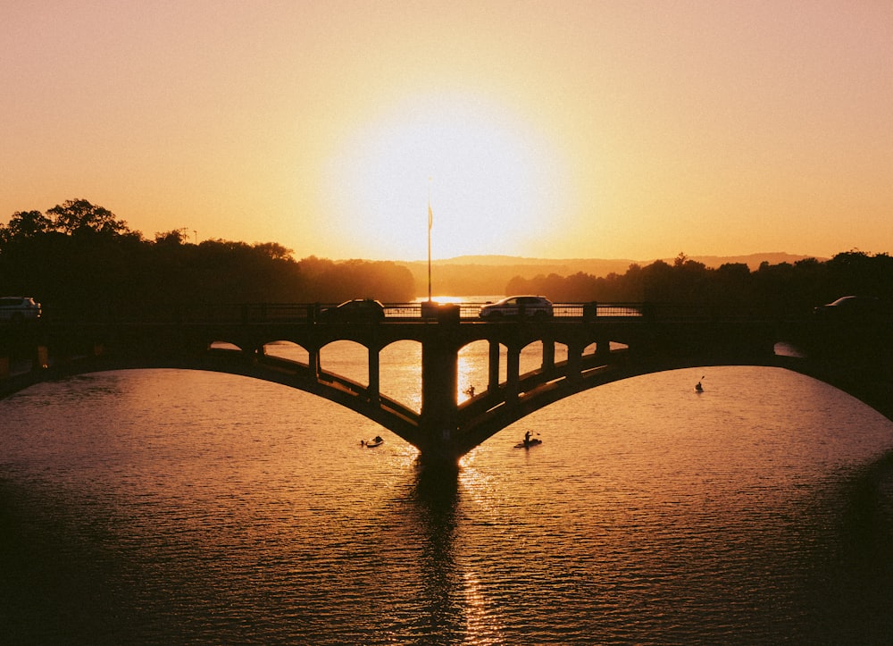 silhouette of bridge over body of water during sunset