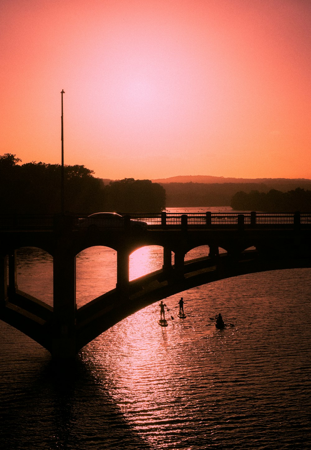 silhouette of bridge over body of water during sunset