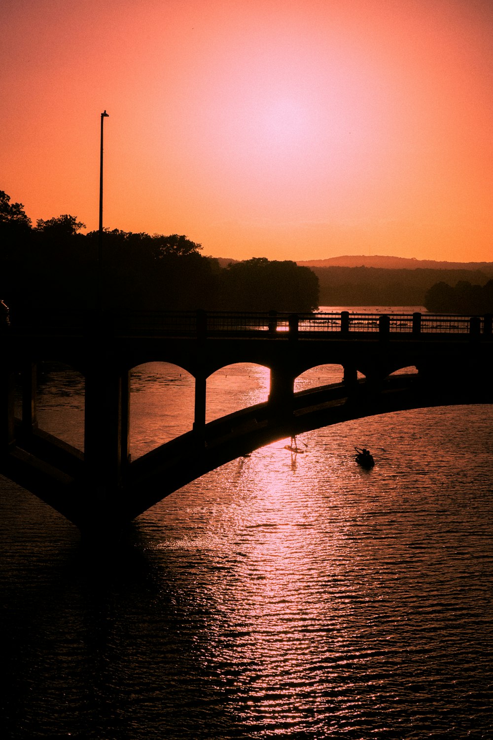 silhouette of bridge over body of water during sunset
