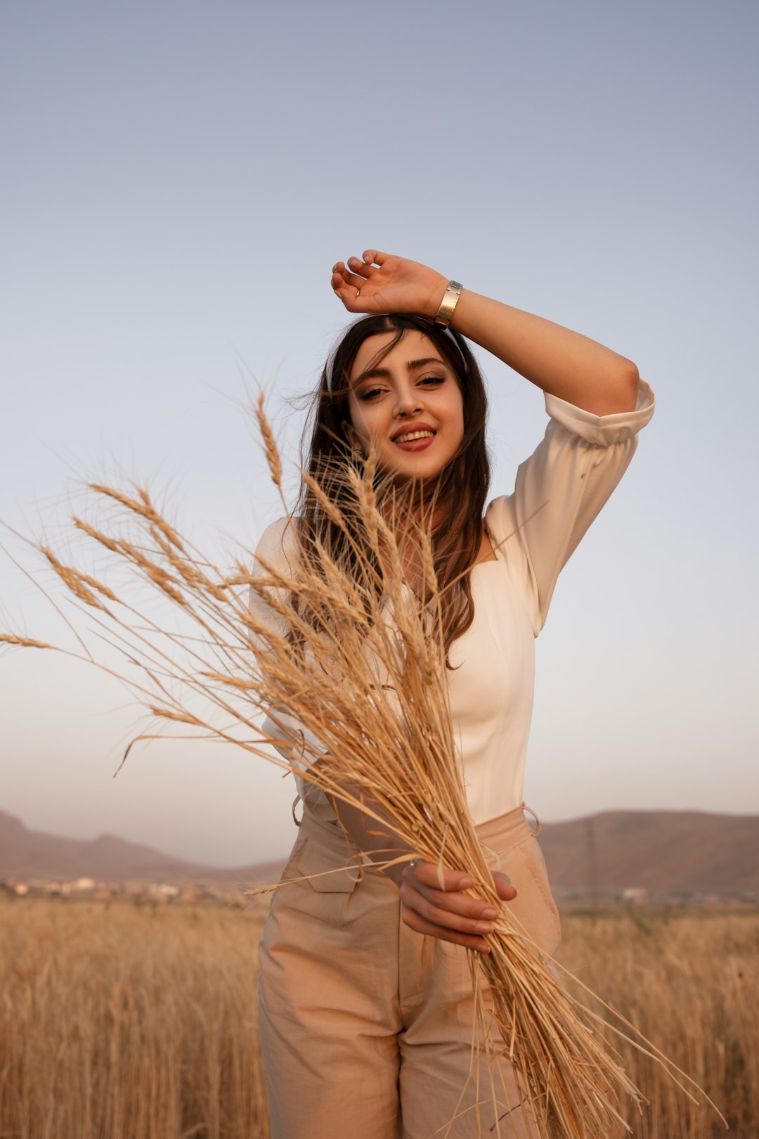 woman in beige long sleeve shirt standing on brown field during daytime