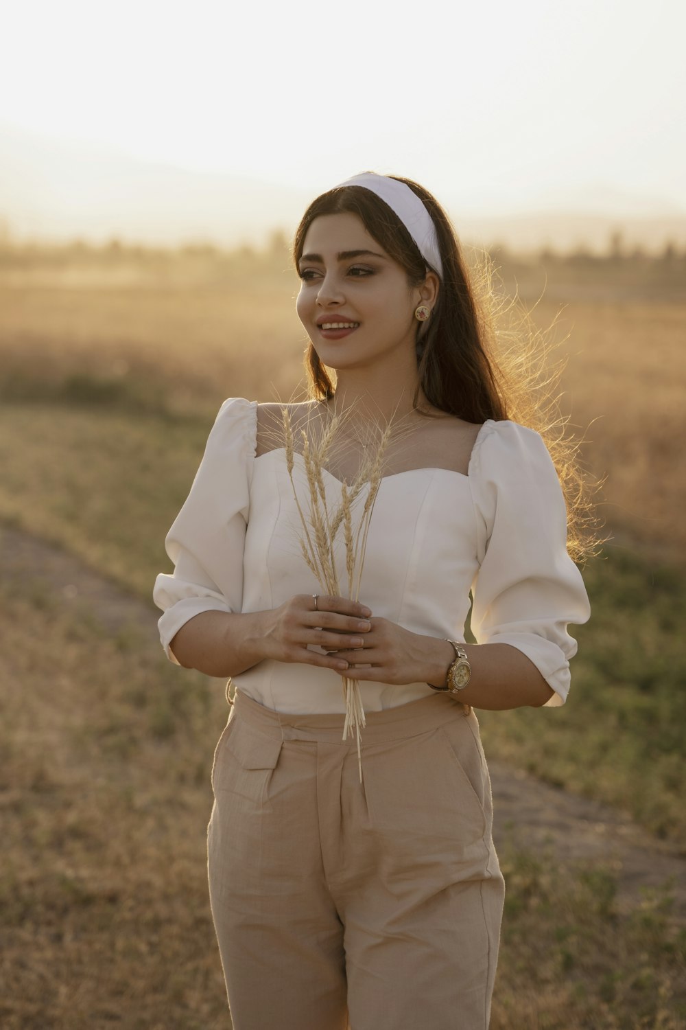 woman in white long sleeve shirt standing on brown grass field during daytime