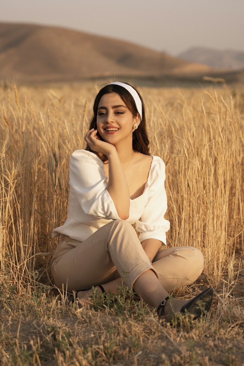 woman in white long sleeve shirt sitting on brown grass field during daytime