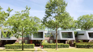 Modern residential building with clean lines and large windows surrounded by greenery.