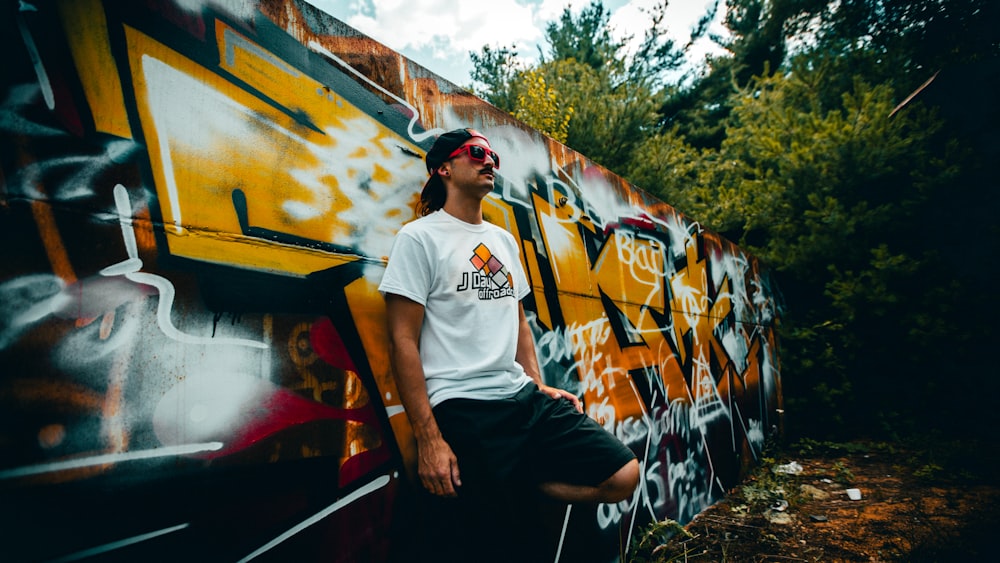 man in white crew neck t-shirt and black pants sitting on red and yellow train